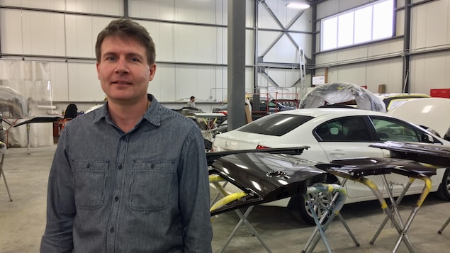 Un homme pose pour la caméra dans un centre de carrosserie automobile. Un homme pose pour la caméra dans un centre de carrosserie automobile.