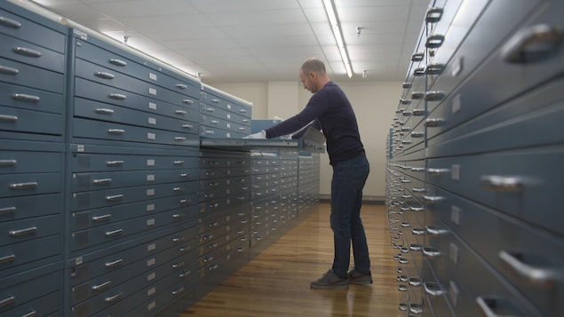 Un homme place un document dans un vaste classeur. Un homme place un document dans un vaste classeur.