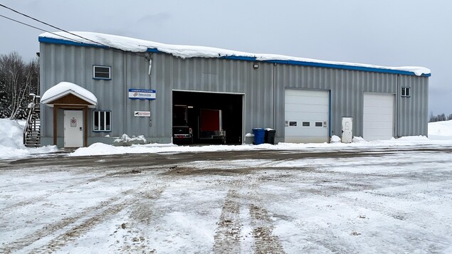 La caserne des pompiers en hiver. Il y a trois portes de garage dont une est ouverte.