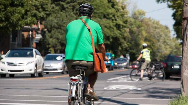 Un cycliste circule dans les rues et porte un casque.