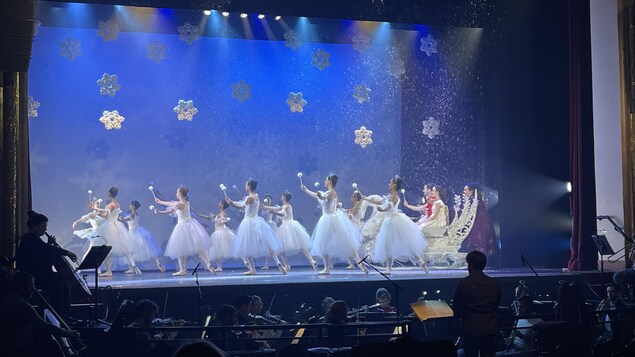 Une dizaine de ballerines sur la scène devant un orchestre.