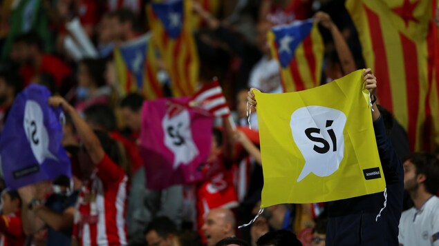 Des indépendantistes catalans brandissent des signes avec le mot « oui » écrit dessus.