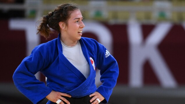 Les mains sur les hanches, Catherine Beauchemin-Pinard regarde à sa gauche sur le tatami.