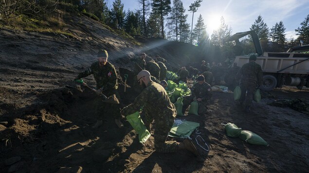 Des soldats remplissent des sacs de sable pour aider à protéger les membres de la Première Nation de Chawathil, près de Hope, en Colombie-Britannique, le dimanche 21 novembre 2021.