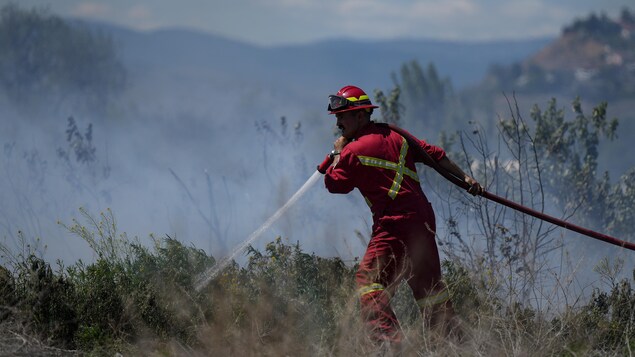Un pompier arrose un amas de broussailles en feu dans les environs de Kamloops, en Colombie-Britannique, le lundi 5 juin 2023.