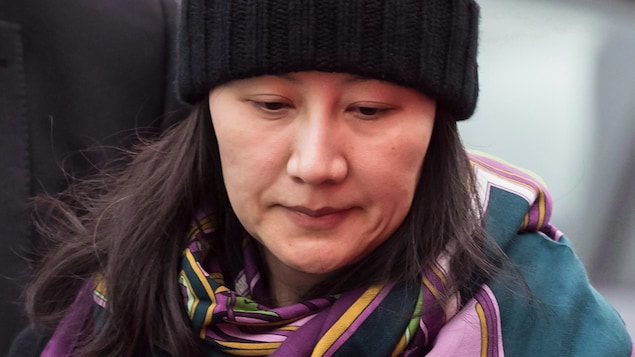 La directrice financière de Huawei, Meng Wanzhou, portant tuque et châle en compagnie d'un agent de sécurité à Vancouver, le 12 décembre 2018.