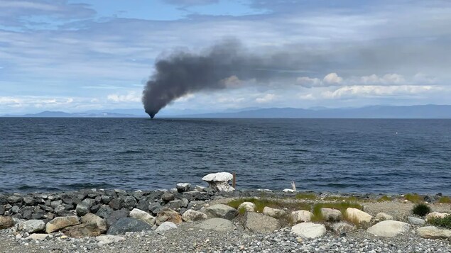 Un panache de fumée s'échappe d'un bateau de plaisance de 40 pieds en feu dans le détroit de Georgia, près de Qualicum Beach, sur l'île de Vancouver, le lundi 23 mai 2022.