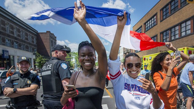 Deux jeunes filles soulèvent un drapeau français en souriant Deux jeunes filles soulèvent un drapeau français en souriant