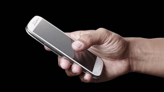 Un homme tient un téléphone intelligent.