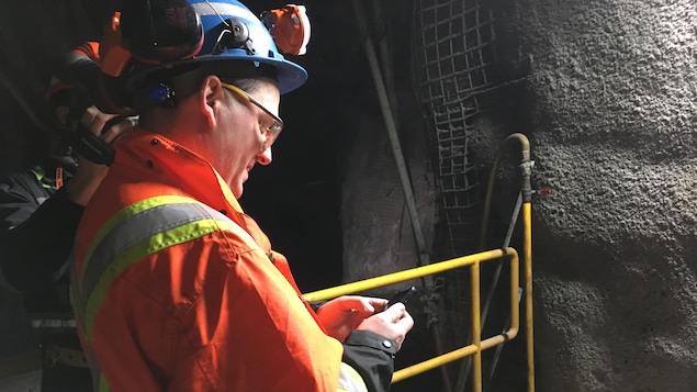 Un mineur utilise un téléphone cellulaire sous terre.
