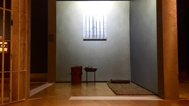 Reproduction de la cellule de prison de Mandela. Dans la cellule, on voit un tapis au sol, une petite table et une poubelle qui servait à Mandela de toilette. Reproduction de la cellule de prison de Mandela. Dans la cellule, on voit un tapis au sol, une petite table et une poubelle qui servait à Mandela de toilette.