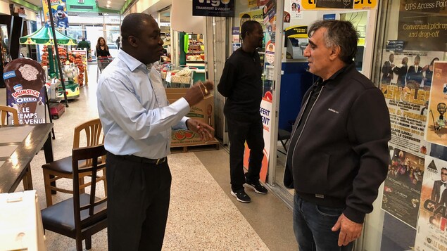 Okkas Altunatmaz d’origine turque et propriétaire de la Fruiterie Savannah discute avec le propriétaire de l'entreprise voisine, Monode Gracia, d'origine haïtienne qui possède Ges Taxi.