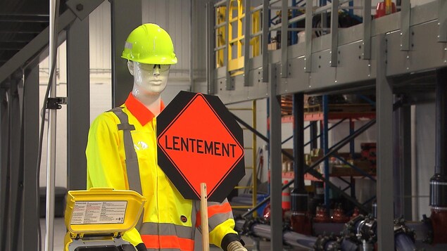Un mannequin tient un panneau de circulation.