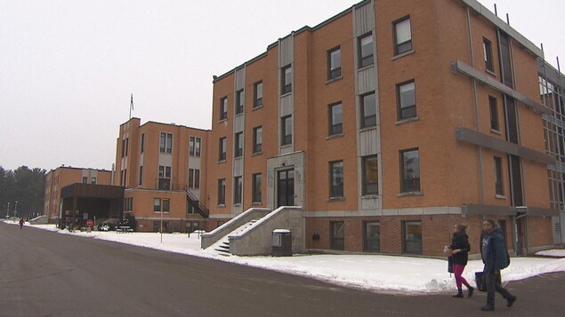 Une femme et un homme circulent à pied devant façade du Centre multiservices de santé et de services sociaux Cooke.