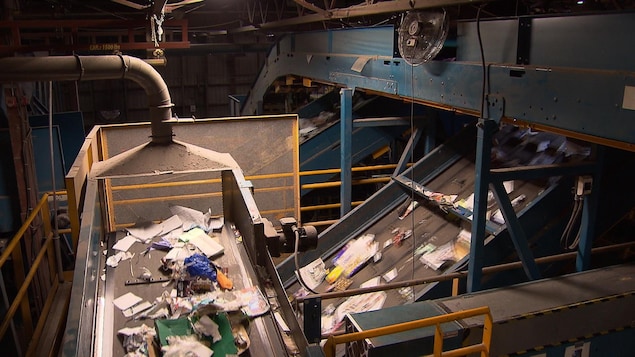 Des matières recyclables défilent sur des tapis roulants à l'intérieur d'un centre de récupération.