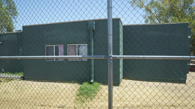 Un bâtiment en béton gris derrière une clôture de métal.