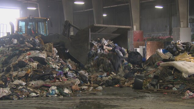 Un camion pousse des déchets dans le centre de tri.