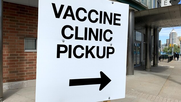 Un panneau indique en anglais où se fait l'embarquement vers le centre de vaccination.