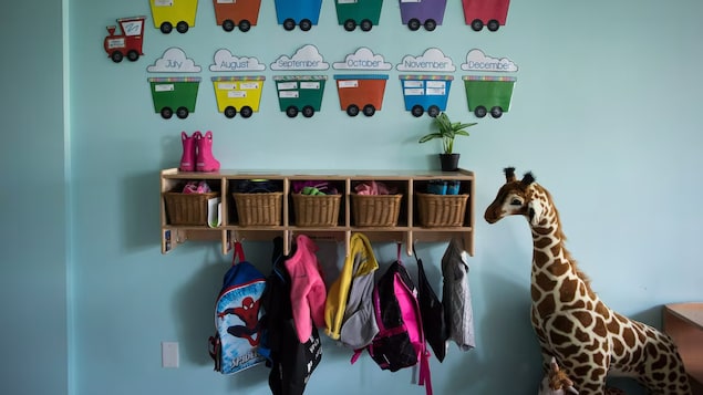 Crochets avec vêtements d'enfants et grande peluche de girafe. 