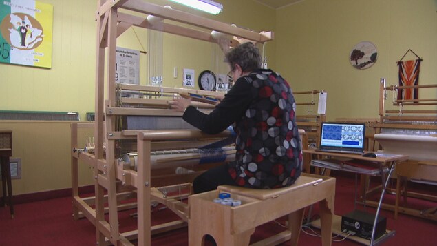 Une femme assise derrière un métier à tisser.
