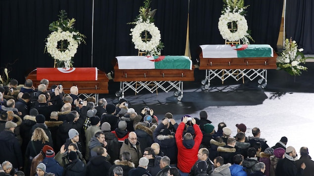 Les cercueils de victimes de l'attentat de Québec sont exposés devant une foule compacte, lors des funérailles qui se tiennent à l'aréna Maurice-Richard, à Montréal. Les cercueils de victimes de l'attentat de Québec sont exposés devant une foule compacte, lors des funérailles qui se tiennent à l'aréna Maurice-Richard, à Montréal.