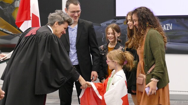 The judge shakes hands with a newly Canadian little girl.