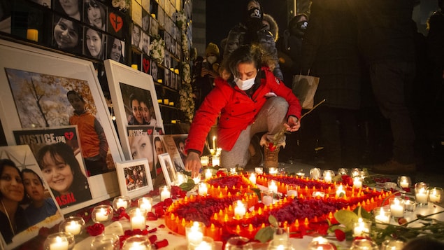 امرأة تضيء شمعة وسط شموع أُخرى مضاءة تحت صور ضحايا تحطم الطائرة الأوكرانية.