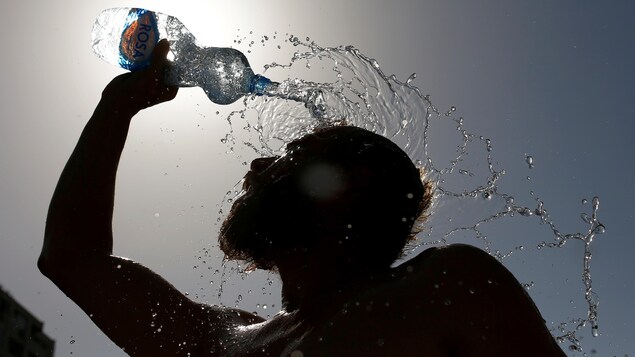 Un homme se rafraîchissant avec une bouteille d'eau