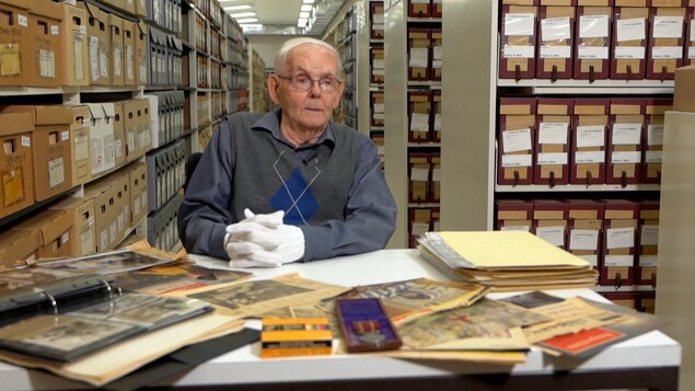 Un homme dans un endroit avec beaucoup de boîtes d'archives.