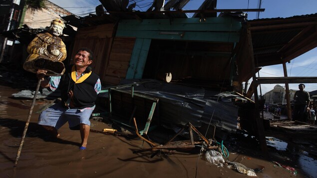 Un homme pleure devant une effigie religieuse parmi les décombres plongés dans l'eau boueuse des inondations au Honduras, en 2010. Un homme pleure devant une effigie religieuse parmi les décombres plongés dans l'eau boueuse des inondations au Honduras, en 2010.