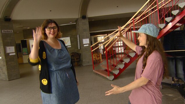 Les deux femmes sont dans le hall de La Cité Francophone pour quelques pas de danse. éemi salue la caméra de la main.
