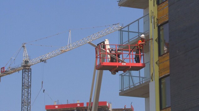 Homme dans les airs près d'un bâtiment et d'une grue.