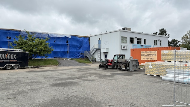 La structure d’un aréna en réparation est recouverte de bâches de protection.