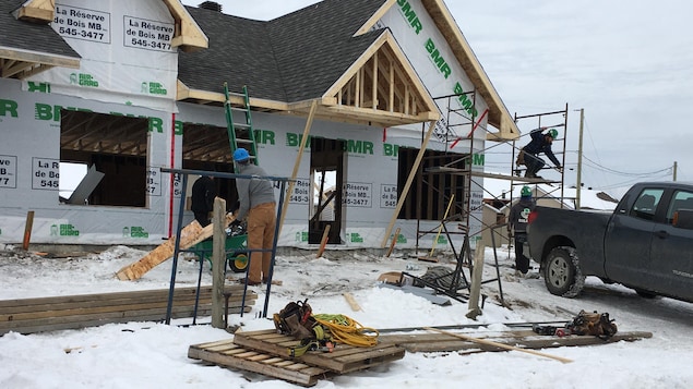 Des travailleurs construisent une maison à Saguenay.