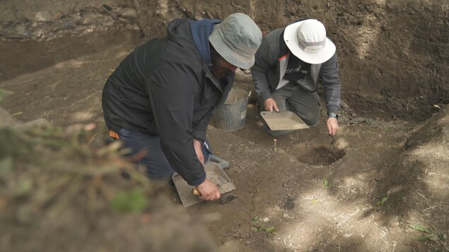 Deux archéologues fouillent dans le sol.
