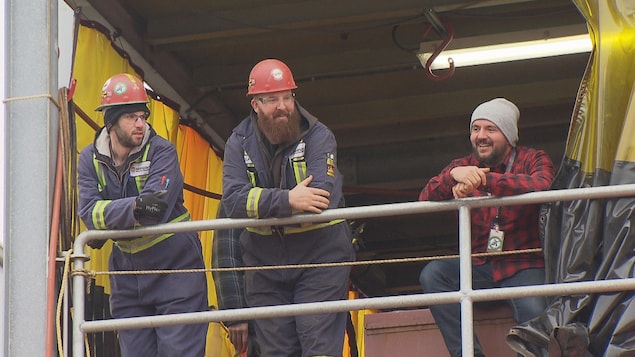 Les trois hommes sont accoudés à une barrière. Les trois hommes sont accoudés à une barrière.