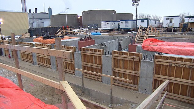 Un chantier de construction, où l'on voit des roulottes, de grosses structures et des panneaux de bois.