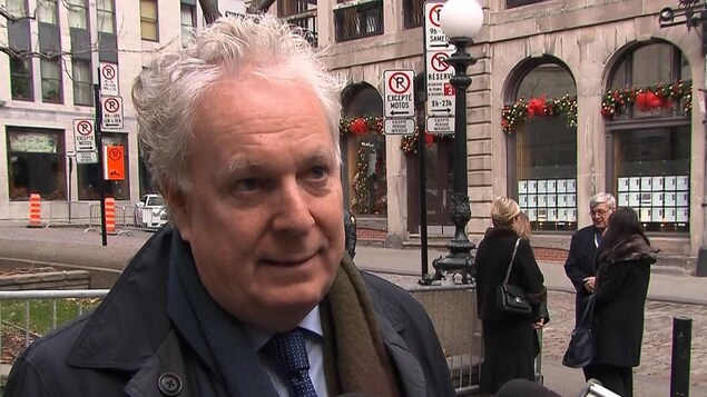 Jean Charest debout devant des micros. Jean Charest debout devant des micros.