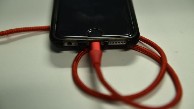 Un fil de chargement rouge est branché dans un iPhone.