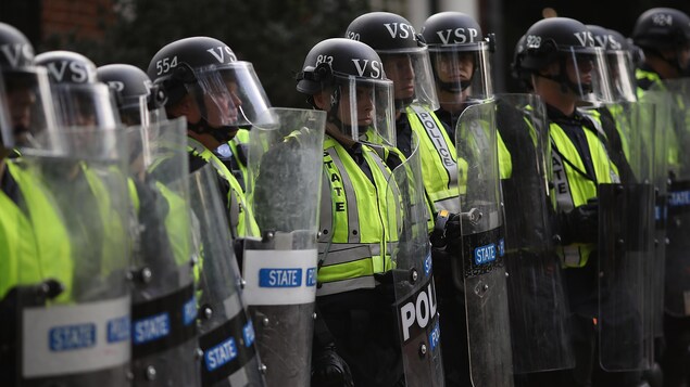 Des policiers antiémeutes se tiennent en rang. Des policiers antiémeutes se tiennent en rang.