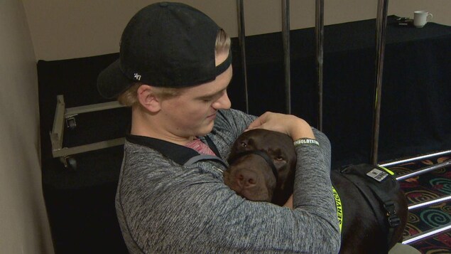 Un chien pose sa tête sur la poitrine d'un jeune homme portant une casquette à l'envers. Un chien pose sa tête sur la poitrine d'un jeune homme portant une casquette à l'envers.