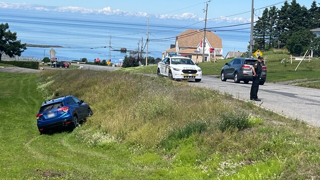 Un agent de la Sûreté du Québec se trouve près d'un véhicule qui est dans le fossé.