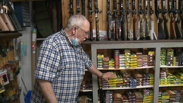 Fernand Lebrasseur devant un étalage de munitions et de fusils.