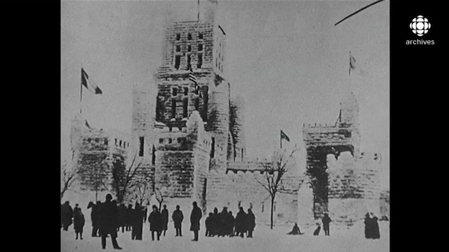 Photo en noir et blanc d'un château de glace décoré de quelques drapeaux, avec un foule de gens devant Photo en noir et blanc d'un château de glace décoré de quelques drapeaux, avec un foule de gens devant