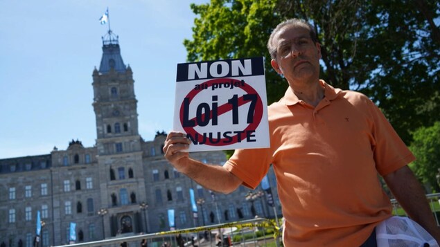 Un homme portant une pancarte en arrière plan l'Assemblée nationale.