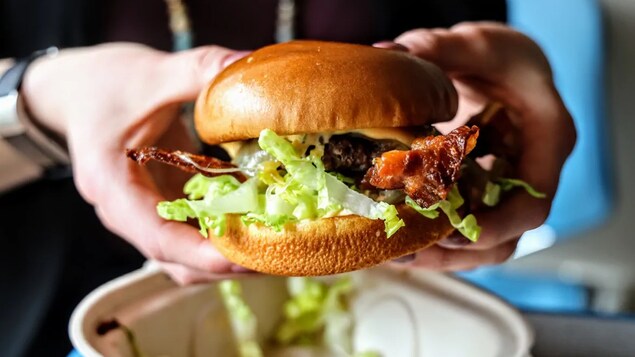 Cheeseburger tenu dans des mains.