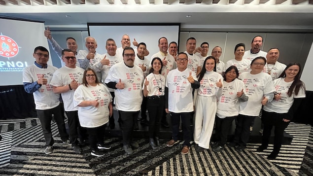 Des membres de l'APNQL posent tous ensemble. Ils portent un T-shirt sur lequel on peut lire : Nos droits, nos voix, nos lois. 