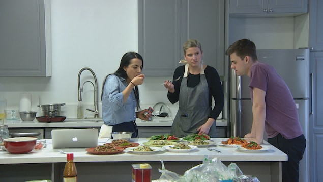 Trois personnes mangent autour d'un comptoir de cuisine. Trois personnes mangent autour d'un comptoir de cuisine.