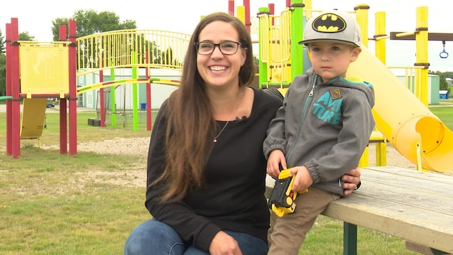 Une mère sourit à la caméra en enlaçant son fils, tous deux assis sur une table de pique-nique dans un parc. Une mère sourit à la caméra en enlaçant son fils, tous deux assis sur une table de pique-nique dans un parc.