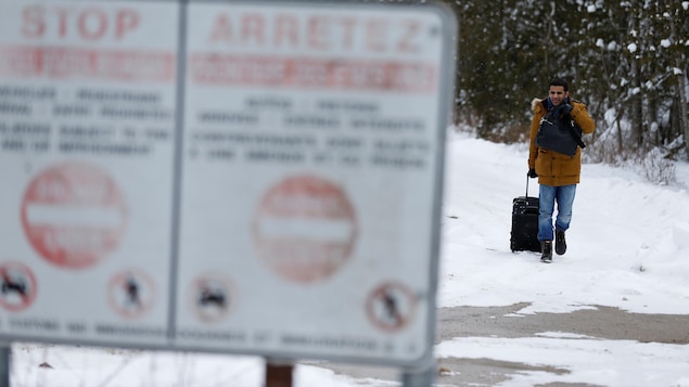 Un homme descend le chemin Roxham en direction de la frontière canado-américaine.